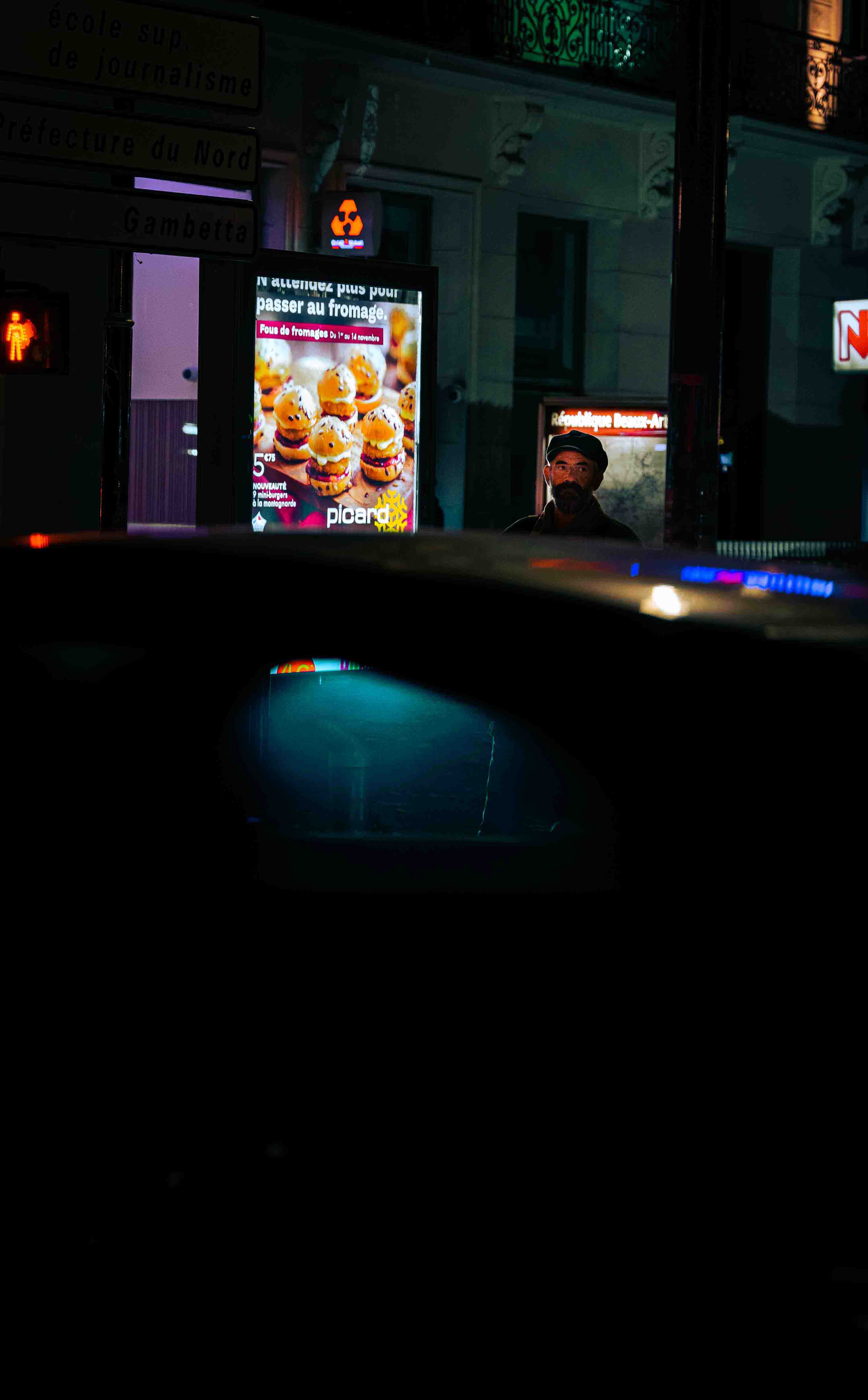 Scène nocturne et publicité lumineuse dans une rue de Lille