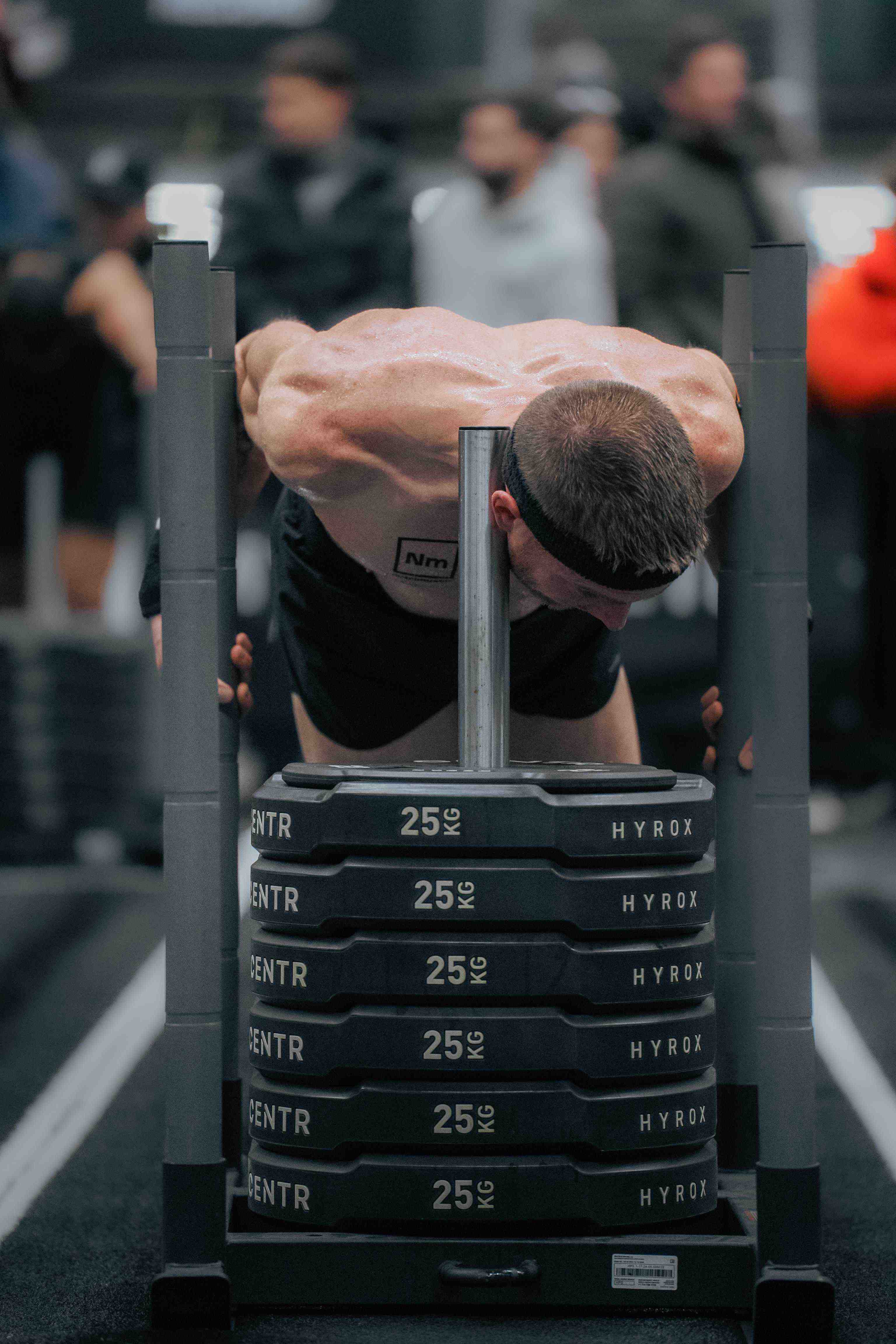 Athlète réalisant le sled push pendant une compétition HYROX